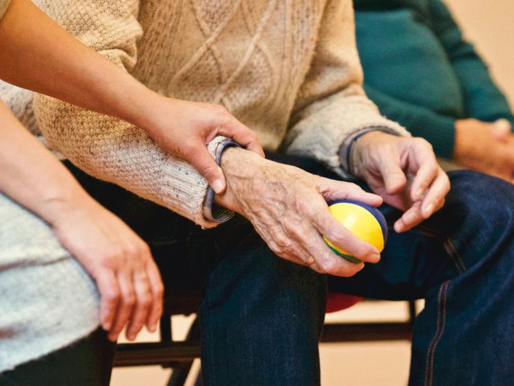 Nurse holding an elderly person's wrist as they hold a ball